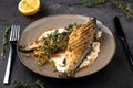 Fried rainbow trout fish with lemon sauce and thyme on black marble table as background Royalty Free Stock Photo