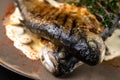 Fried rainbow trout fish with lemon sauce and thyme on black marble table as background. macro view Royalty Free Stock Photo