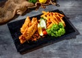 Fried Red Tilapia fish with salad, lime and fries in dish side view on dark background Royalty Free Stock Photo