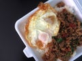 Fried rice with basil with fried egg in foam box.
