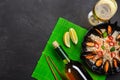 Fried rice with seafood mussels, shrimps, basil in a black plate with wine bottle, wineglass, lemon, chopsticks on green bamboo