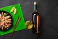 Fried rice with seafood mussels, shrimps, basil in a black plate with wine bottle, wineglass, lemon, chopsticks on green bamboo