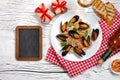 Fried rice with seafood mussels, shrimps and basil in a plate with wine bottle, wineglass, chalk board, towel, toasted baguette