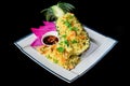 Fried rice with seafood in a pineapple with vegetables on blue plate isolated on black background side view Royalty Free Stock Photo