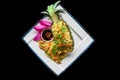 Fried rice with seafood in a pineapple with vegetables on blue plate isolated on black background top view Royalty Free Stock Photo