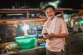 fried rice seller standing holding phone