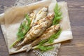 Fried river fish and dill on a paper on a wooden background Royalty Free Stock Photo