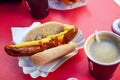 Fried sausage in a bun with mustard and ketchup with coffee in a cafe Royalty Free Stock Photo