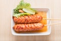 Fried sausage a grill on a stick in sauce on white dish, food in Royalty Free Stock Photo