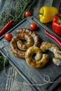 Fried sausage with herbs and spices, wooden background. Ring of baked homemade sausage. Served on a wooden board with greens and Royalty Free Stock Photo