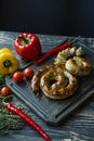 Fried sausage with herbs and spices, wooden background. Ring of baked homemade sausage. Served on a wooden board with greens and Royalty Free Stock Photo