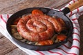 Fried sausage with onions and tomatoes in a pan closeup, rustic Royalty Free Stock Photo