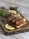 Fried sausages with bacon on a wooden board.