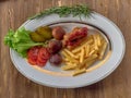 Fried sausages with French fries, salad and mushrooms Royalty Free Stock Photo