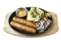 Fried sausages with mashed potatoes, pickles and mustard sauce served on a cast-iron frying pan. Appetizing traditional lunch. Royalty Free Stock Photo