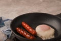 Fried sausages in a pan with scrambled eggs close-up and copy space. Boiled sausages and fried eggs breakfast in a frying pan Royalty Free Stock Photo