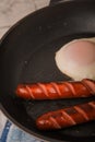 Fried sausages in a pan with scrambled eggs close-up and copy space. Boiled sausages and fried eggs breakfast in a frying pan Royalty Free Stock Photo