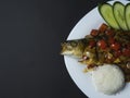 Fried sea bass fish in oil with sweet and sour sauce, vegetables and a portion of rice on a white plate Royalty Free Stock Photo