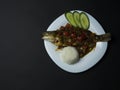 Fried sea bass fish in oil with sweet and sour sauce, vegetables and a portion of rice on a white plate Royalty Free Stock Photo