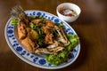 Fried sea bass fish in white plate with spicy and sweet sauce in Thai style .  crispy Thai style deep fried whole sea bass fish se Royalty Free Stock Photo