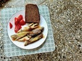 Fried sea bass a slice of black bread on a white plate on a stool in the background of the terrace floor Royalty Free Stock Photo
