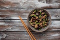 Fried shiitake mushrooms with green onions in a bowl on a wooden old background. Japanese vegetarian food. Top view