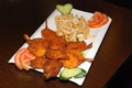 Fried shrimps with French fries and vegetables on the white plate Royalty Free Stock Photo