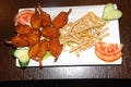 Fried shrimps with French fries and vegetables on the white plate Royalty Free Stock Photo