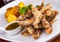 Fried small fish and baked potato on white plate