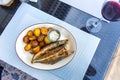 Fried smelt with boiled potatoes and mushroom sauce on white plate. Delicious rustic lunch