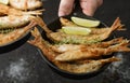 Fried smelt in a frying pan on the table with spices, lime and thyme