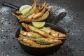 Fried smelt in a frying pan on the table with spices, lime and thyme