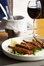 Fried smelt with lemon and vegetables on the table with a glass of red wine. A small fish. Mediterranean cuisine