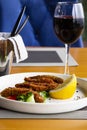 Fried smelt with lemon and vegetables on the table with a glass of red wine. A small fish. Mediterranean cuisine