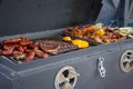 Fried smoked sausages, fried chicken wings, peppers and paprika, toasted corn on fire, street food, mobile barbecue, trailer on wh Royalty Free Stock Photo