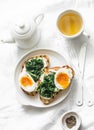 Fried spinach, labne, boiled eggs sandwiches and green tea - delicious healthy breakfast or snack on a light background