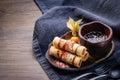 Fried spring roll asian dessert on wooden table background. Banana spring rolls with chocolate dressing, berry jam and physalis