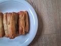 Fried spring rolls on a white plate with a wooden background