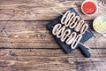 Fried squid rings on a skewer with tomato sauce and lemon. Dark wooden background copy space. Top view