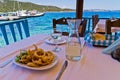 Fried squid and white wine in a shade of a typical greek taverna in a harbour at Amoulani island Royalty Free Stock Photo