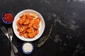 Fried sweet potatoes with tomato and garlic sauce on a dark stone background. Top view, flat lay Royalty Free Stock Photo