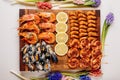 Fried tails of langoustines and fried mussels with sauce and fried shrimps and sliced lemon on wooden cutting board and jacinths Royalty Free Stock Photo