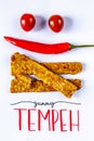 Fried tempeh decorated with chilly and tomato smile. YUMMY TEMPEH caption. Top view. Vertical image. Royalty Free Stock Photo