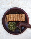 Fried tempeh and green chili sauce are placed on a clay mortar. Tempe is a typical Indonesian food made from fermented soybeans.