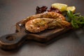 Fried tiger shrimps with lemon, sun-dried tomatoes and greens or rukkola on a dark wooden cutting board. Royalty Free Stock Photo