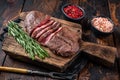 Fried Top Blade or flat iron roast beef meat steaks on wooden board with rosemary. Dark wooden background. Top View