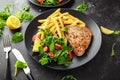 Fried Tuna Steaks on Black Plate with Fresh Green, Tomato Salad, lemon and french fries. healthy sea food Royalty Free Stock Photo