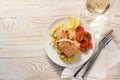 Fried tuna steaks on savoy cabbage, tomatoes and lemon served with wine on a plate and a white painted wooden table with napkin Royalty Free Stock Photo