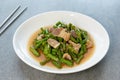 Fried yardlong beans with streaky pork in white dish on concrete table