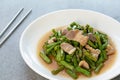 Fried yardlong beans with streaky pork in white dish on concrete table